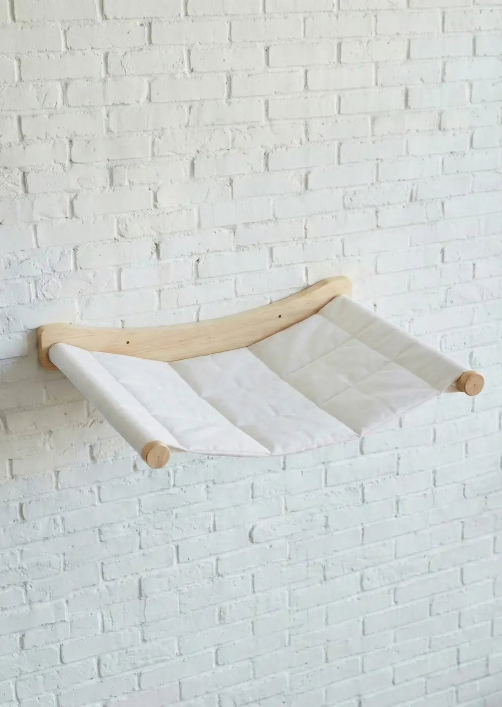 The Purrfait Perch Lounge, a minimalist floating cat bed with a curved natural wood bracket and suspended fabric design, perfect for creating a modern vertical resting spot.